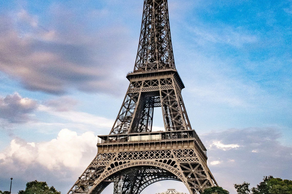 The Eiffel Tower in Paris framed against a blue sky, representing the diaspora communities abroad that Oseaeyo Auto Dealership customers buy cars from for family in Ghana